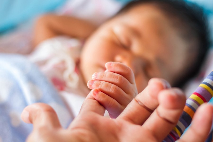 новорожденный держится за палец